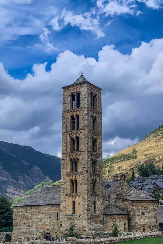 Stunning view of a Romanesque church tower amidst mountains under a bright blue skyin andorra